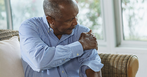 A man grabbing his shoulder in pain.